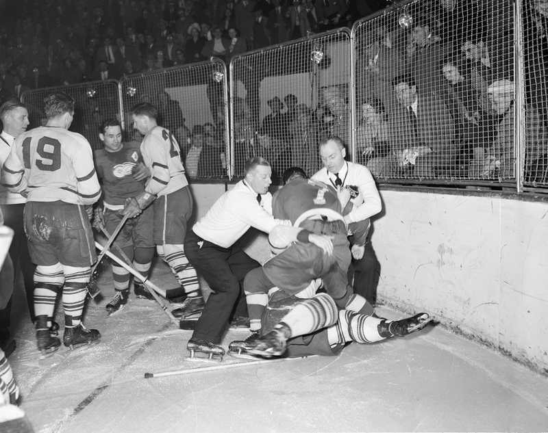 The extremely good original AP caption: “Officials strain to pull Detroit Red Wing forward Ted Lindsay off an unidentified Toronto Maple Leafs player in a squirmish during the third period of a game two playoff matchup at the Detroit Olympia on March 30, 1950 in Detroit, MI.”